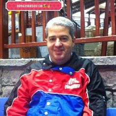 a man sitting on a blue bench wearing a red, white and blue raincoat