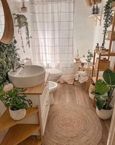 a bathroom with wooden floors, white walls and plants on the counter top next to the sink