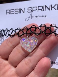 Each resin pendant is handmade to order, therefore no two chokers are identical! However, I try to get as close to the listing photos as possible :) One size fits all black elastic tattoo choker necklace. Made with clear epoxy resin and white chunky holographic glitter ✨ Heart width is approximately 19mm Thanks for visiting my shop! 🌈 Trendy Black Heart-shaped Choker, Trendy Black Heart Choker, Cute Adjustable Black Choker, Black Heart-shaped Jewelry For Festivals, Black Heart-shaped Festival Jewelry, Cute Black Heart-shaped Necklaces, Cute Black Heart Necklace, Cute Black Heart-shaped Necklace, Black Kpop Style Necklace For Gift