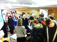 a group of people standing around each other in a room with posters on the wall