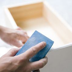 a person holding a blue sponge on top of a piece of paper in their hand