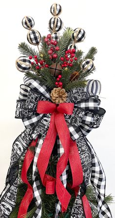 a black and white christmas wreath with red ribbon, pine cones and berries on it