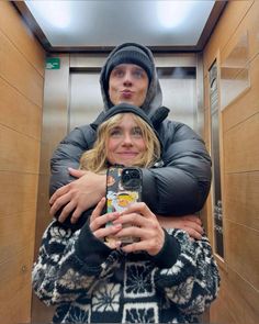 a man and woman taking a selfie in an elevator with their arms around each other