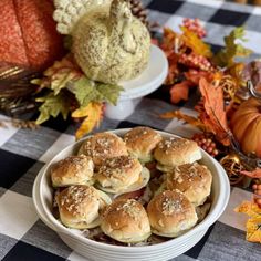 small sandwiches in a white bowl on a checkered tablecloth next to pumpkins and gourds