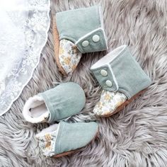 two pairs of baby shoes sitting on top of a fur rug