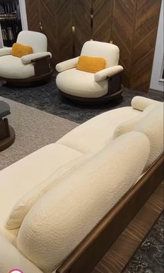 a living room filled with white couches and wooden tables on top of carpeted flooring