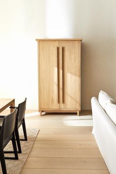 a white couch sitting next to a wooden cabinet on top of a hard wood floor