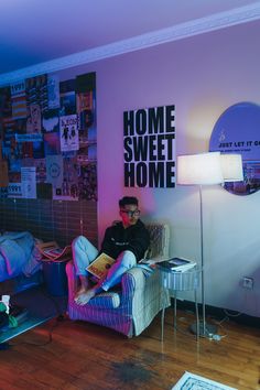 a man sitting on a chair in front of a wall with posters and lights behind him