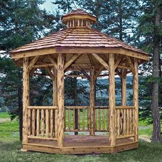 a wooden gazebo sitting on top of a lush green field next to tall trees