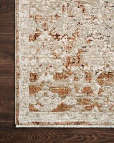 an area rug with brown, orange and white colors on top of wooden flooring