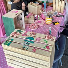 people are sitting at a table with wooden boxes and other crafting supplies on it