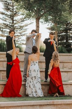 a group of people standing around each other in formal dress and tuxedo attire