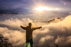 a man standing on top of a mountain surrounded by clouds