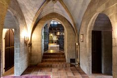 an arched hallway leading to another room with red rugs on the floor and light fixtures