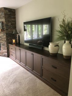 a flat screen tv sitting on top of a wooden dresser next to a fire place