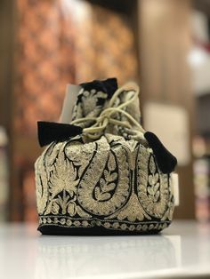 Complete your traditional looks with this lovely potli bag on your wrist, which is trendy yet compact enough to carry your essentials in style. This potli bag will be a pretty inclusion in your accessory collection and perfect for taking in a party. This bag can also be used as a wedding favour bag. It is perfect as a gift for weddings, bridal showers, baby showers, wedding receptions - excellent to fill with candy, dry fruits, sweets, herbs, soap, something remarkable for your guests that no one will leave behind! --------------------------------------------------------------------  Product Details - Condition Brand New  - Potli Bag with all-over Kashmiri Zari Embroidery and Drawstrings for closing. - Fabric: Velvet - Colour: Black - Size: 7" High and 5" Base (17.78 cms High and 12.7 cms Vintage Style Bag, Potli Bag, Potli Bags, Bags Vintage, Wedding Favor Bags, Velvet Color, Women Bags Fashion, Embroidered Bag, Bags Fashion