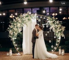 a bride and groom kissing in front of an arch decorated with flowers, candles and bubbles