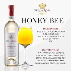 a bottle of honey bee wine next to a glass filled with orange juice and lemon