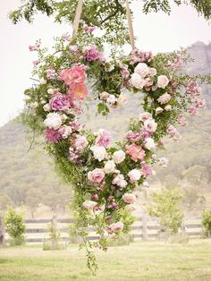 a heart shaped wreath with flowers hanging from it's sides and the words above it