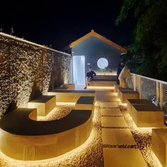 an outdoor area lit up at night with lights on the walls and steps leading to it