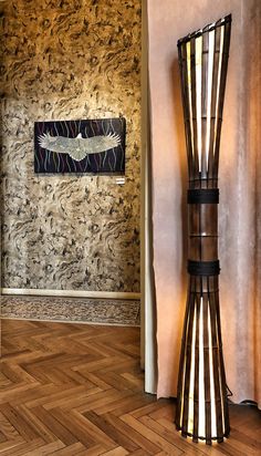 a tall lamp sitting next to a painting on the wall in a room with wood flooring