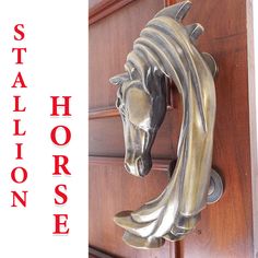 a metal horse head mounted to the side of a wooden door with red lettering on it