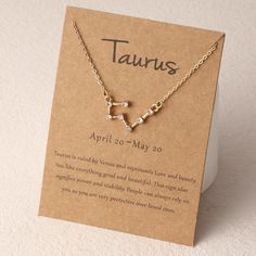 the taurus zodiac sign necklace is displayed on a card