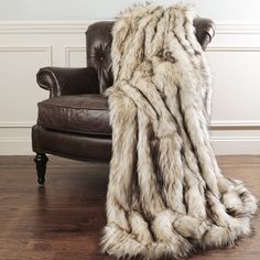 a chair with a fur blanket sitting on it's back in front of a wall