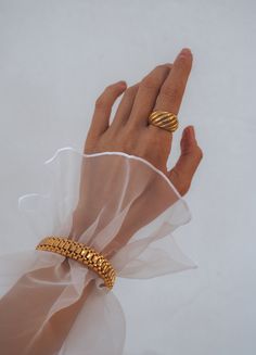 a woman's hand with two gold rings on her fingers and a white background