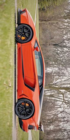 an orange sports car is parked on the grass