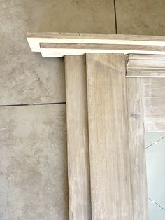 an unfinished piece of wood sitting on top of a tile floor next to a wall