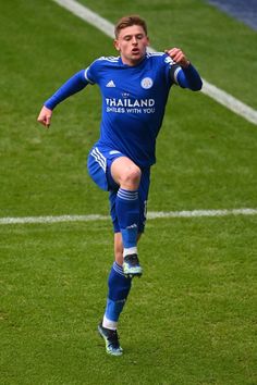 a young man kicking a soccer ball on top of a field