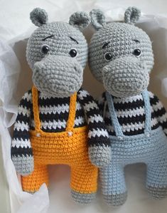 two crocheted stuffed hippos sitting next to each other in a box