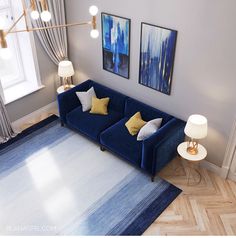 a blue couch sitting in the middle of a living room next to a lamp and two paintings