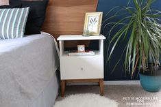 a bed room with a neatly made bed and a potted plant on the nightstand