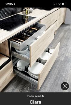 an open drawer in the middle of a kitchen with plates and pans on it