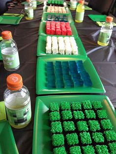 a table topped with green trays filled with cupcakes and cake covered in frosting