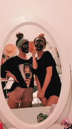 two people with masks on taking a selfie in front of a mirror that is reflecting their faces