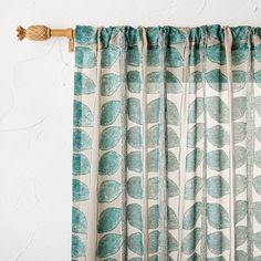 the curtains are hanging on the wall with wood rods in front of them and green leaves