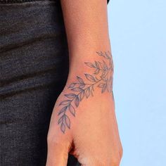 a woman's hand with a tattoo on her left wrist and an olive branch in the middle