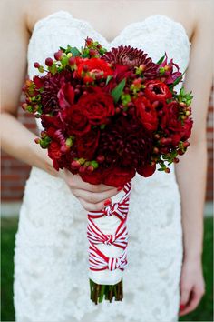 a bride holding a bouquet of red flowers