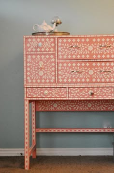 an old dresser is painted in pink and white with floral designs on the drawers, along with a bench