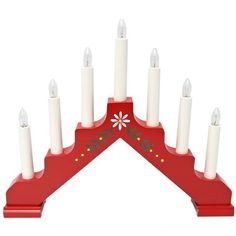 a red candle holder with white candles on it's sides and an ornament in the middle