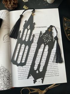 an open book with some tassels and scissors on the table next to it