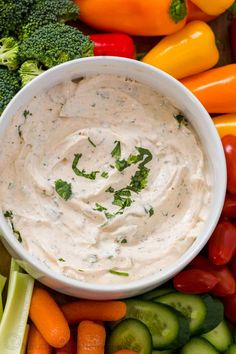 a white bowl filled with dip surrounded by vegetables