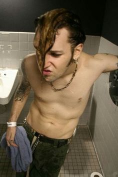 a man with long hair standing in a bathroom