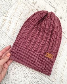 a hand is holding up a knitted beanie