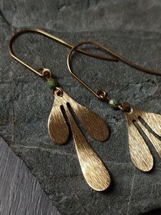 Brushed brass leaves on elegant elongated brass ear wires, with a little pop of color from a patterned turquoise Czech glass bead in the middle. Details: Total length: ~5.5cm Brass ear wires  glass bead size: ~3.5mm Find more Silver and Moss earrings here:  https://www.etsy.com/shop/silverandmoss?section_id=32748105 + Please note that all jewelry is handmade and may vary slightly <3  The best efforts have been made to take photos representing the true colors of the item, however colours may vary Bohemian Brass Leaf Jewelry, Bohemian Leaf-shaped Brass Jewelry, Bohemian Bronze Jewelry With French Hook, Handmade Bronze Brass Teardrop Earrings, Handmade Adjustable Brass Teardrop Earrings, Turquoise Teardrop Brass Jewelry, Bohemian Gold Leaf Jewelry, Gold Leaf-shaped Copper Jewelry, Unique Gold Teardrop Earrings Nickel Free