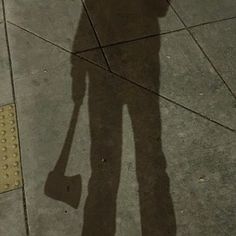 the shadow of a person holding an umbrella over their head while standing on a sidewalk