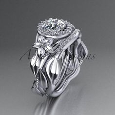 a white gold diamond ring with leaves and flowers on the side, surrounded by diamonds